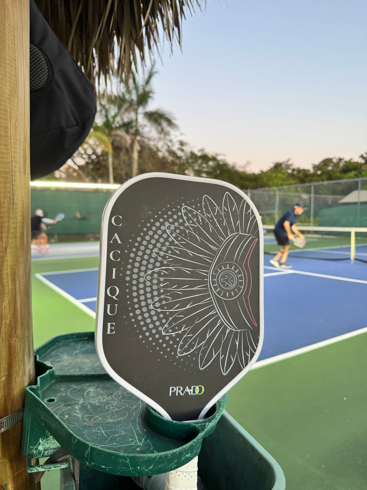 Cacique pickleball paddle on a stand in a pickleball court 