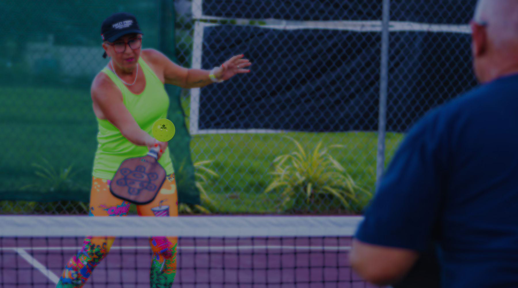 Two people playing paddleball on a court with a green background