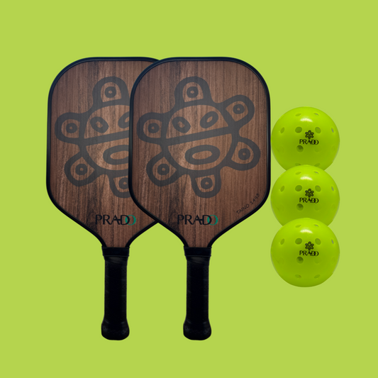Taíno Sun Pickleball Starter Kit with two carbon fiber paddles featuring Puerto Rican design and three USAPA-approved outdoor balls on green background
